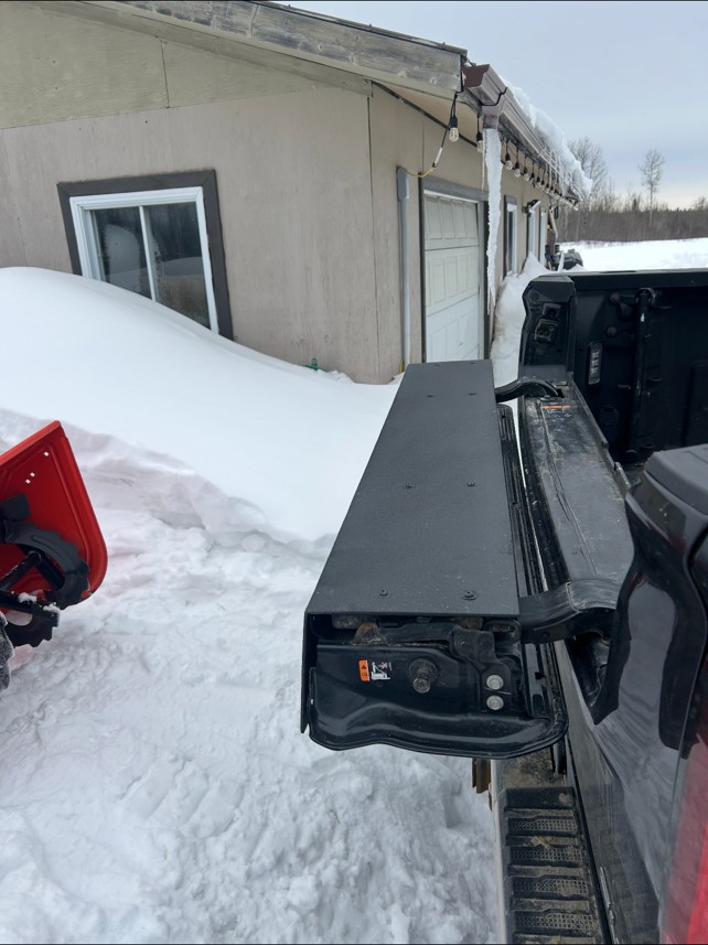 New custom steel tailgate cap installed on a GMC pickup, close-up showing mounting hardware